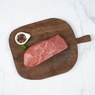 Corte de carne posta negra sobre una tabla de cortar de madera