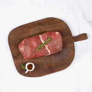 Corte de carne posta rosada sobre una tabla de cortar de madera